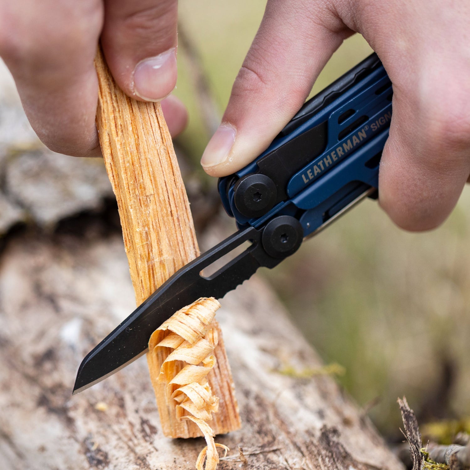 Person using the combo knife on a Nocturnal Leatherman Signal to shave wood