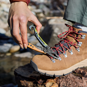 Person using an Aurora Leatherman Skeletool CX to fix a hiking boot lace hook